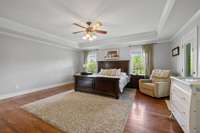 Primary bedroom adorned with a sophisticated trey ceiling, adding depth and elegance to the space. Two windows welcome natural light, illuminating the room with a soft glow.