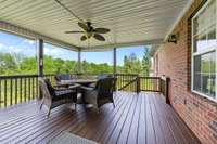 A freshly painted covered deck, adorned with a crisp coat of pain that enhances its inviting charm.  Pull-down shades offer versatility. Ceiling fans gently stir the air creating a pleasant breeze on warm days.