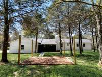 YOU HAVE TO SEE THIS IS PERSON TO GET THE FEELING OF PEACE AND QUIET! THIS IS THE BACK OF THE HOME LOOKING AT THE SCREENED-IN PATIO THAT IS ATTACHED AND THE OUTDOOR PATIO WITH LIGHTS TO ENJOY GRILLING OUT, A FIRE PIT AND LOOKING UP AT THE STARS.