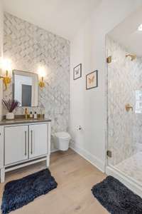 This full bathroom on the main level offers designer finishes, Kohler plumbing, and high-end tile.