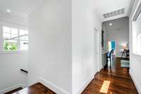 Upper level back hallway takes you from the recreation room to the primary wing. The door to the left in the picture is the pocket door to the laundry room followed by the back staircase that takes you down to the kitchen.