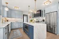 The kitchen features marble counters, a waterfall island and high end appliance. The door opens to the covered back patio.