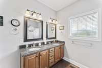 Downstairs primary bath with double vanities, walk-in shower and washer and dryer closet