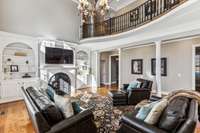 Showcasing arched bookcases flanking the gas fireplace, column detail and coffered ceiling with a large chandelier, this room is rich in classic architectural elements.