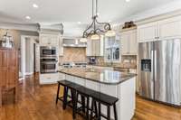 This gorgeous custom Kitchen combines style & efficiency. All of the amenities you could want - wood cabinets, granite counters, tile backsplash, recessed and under cabinet lighting, large pantry, and black light fixture over the island.