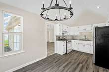 Enjoy abundant natural light, high ceilings, and white cabinets in this adorable eat-in kitchen.