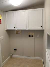 Utility room just off of the kitchen and the covered back porch, great lighting, and cabinet space.