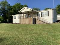 A relaxing covered front porch is perfect for your morning coffee or simply watching your children play in this large ONE-ACRE yard.