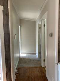 The hallway leading to a full bath and three bedrooms