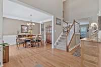 Foyer with hardwood looking into formal dining room.  Wainscotting, crown molding and framed openings