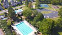 Aerial view of neighborhood amenity area.  Three pools which include a Junior Olympic size pool and a toddler pool with splash features. Neighborhood has it's own youth swim team