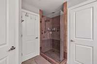 Large tiled walk-in shower. Designated water closet. Door to the left is a linen closet.