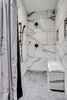 Master Bathroom tiled shower with 2 separate controlled shower heads and shower bench