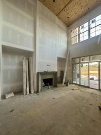 Two-story Great Room with 23 foot ceilings, wood-burning fireplace and built-ins. *this home is under construction Photo taken 9/5/24