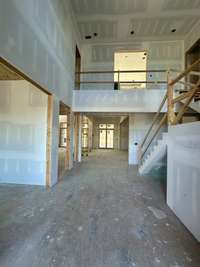 Two-story Great Room with 23 foot ceilings, wood-burning fireplace and built-ins. *this home is under construction Photo taken 9/5/24