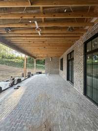 Rear Covered Porch with wood-burning fireplace and outdoor Kitchen with island and grill. *this home is under construction Photo taken 9/5/24