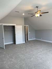 Upstairs spacious bonus room with vaulted ceilings, a ceiling fan, and a closet with french doors.