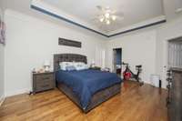 Primary bedroom with fan and hardwood. Door leads to en suite bathroom