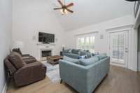 Living room with high ceiling, gas starter fireplace, hardwood and plantation shutters.