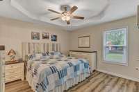 Primary bedroom on main level with trey ceiling, ceiling fan, and two closets for plenty of storage space