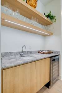 Convenient wet bar w/marble countertops, beverage fridge, lit floating wood shelving