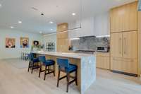 Island w/breakfast bar, waterfall marble countertops, designer lighting