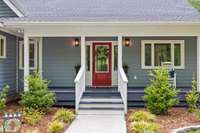 The beautiful landscaping borders the entire wraparound porch and sidewalk to the red front door.   There are two parking spots right across from the front entry for your family & friends.