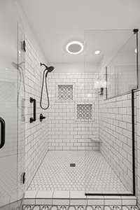 The primary shower is spacious with two niches and even a foot shelf for shaving.