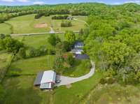 Drone view of back view of house, barn and 3 front pasture areas.