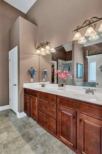 Primary bedrooms private bathroom with long double sink vanity, tile floor and private water closet