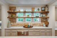 A brick accented wall and reclaimed wood shelves provide a fabulous, stand-out designer element