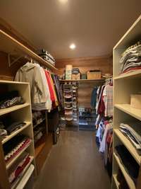 Primary walk-in closet with built in shelving and cedar lined on the non-log side