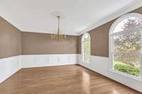 Theformal dining room has deep moldings, arched windows and hardwood floors.