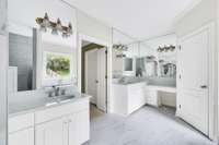 Separate vanities have quartz countertops.