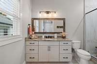 Back guest bathroom with a walk-in tiled shower and marble countertops.