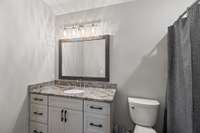 Basement full bathroom with a tub/shower combo and marble countertops.