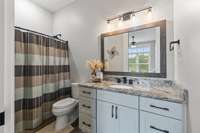 Front guest bathroom with a tub/shower combo, marble countertops, and comfort-height toilet.