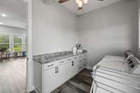 Laundry room with lower cabinets and marble countertops; a perfect workstation.