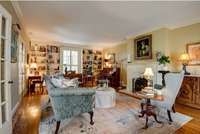 Spacious living room featuring built in bookcases, Italian marble fireplace with gas logs and floor to ceiling windows with plantation shutters.