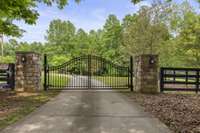 Beautiful iron gated entrance leads down a winding road to the house.