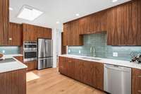 The skylight over head bathes this kitchen in natural light. Striking, and high quality, custom walnut cabinetry, with maple boxes provides abundant storage options. New lighting throughout includes under counter task lights as well.