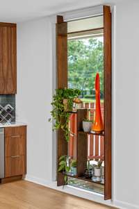 The transition between the dining area and the beautifully remodeled kitchen includes this large window with a geometric shelving unit that provides the home chef with the perfect place for growing culinary herbs.