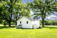 back of home and view of small storage shed