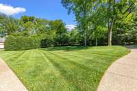 The front landscaping provides substantial privacy from Bowling Avenue, with a beautiful mix of evergreens forming a tall, natural border along the front of the property.