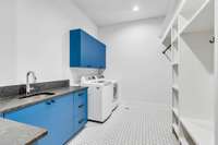 The utility room comes equipped with built in storage, cabinetry, and sink