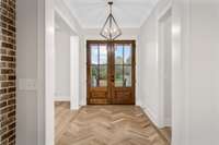 This entry way could be yours to decorate! No rugs needed on this hand laid solid white oak herringbone entrance. The unique wooden & gold light fixture above gives off the perfect glow at night.