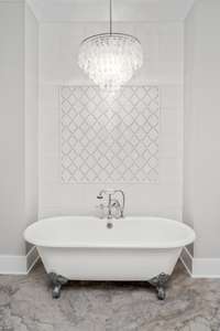 A beautiful picture of the claw foot tub and the solid marble accent wall in the primary bathroom.