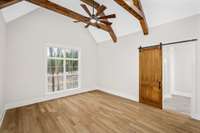 Gorgeous wooden beams in the primary bedroom with great lighting, large windows and a door that takes you out onto the back covered deck.