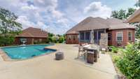 View of the back of home, highlighting the oversized screened in patio, built-in fireplace and grill.