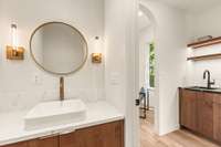 Adjacent to the wet bar is a powder bathroom with luxury finishes and a custom floating cabinet.